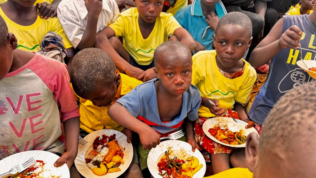 Kinder essen gemeinsam von bunten Tellern