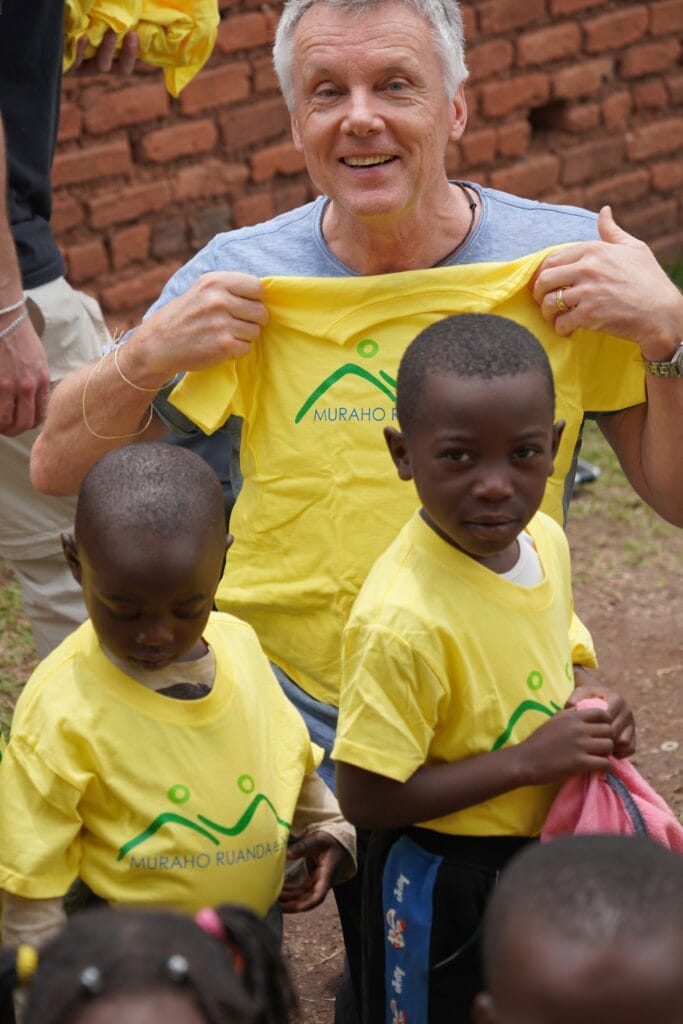 Ein Besucher zeigt ein Muraho-Ruanda-T-Shirt vor zwei Kindern